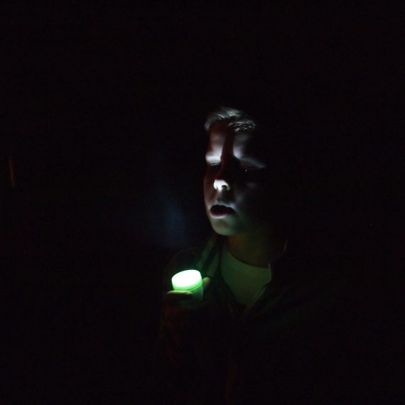 Chłopiec z zieloną latarką w nocy